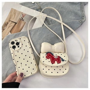 Détail de la coque de téléphone à pois et du mini sac à bandoulière avec broderie poney