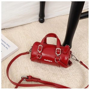 Detail of red cylinder mini bag with silver hardware and adjustable shoulder strap