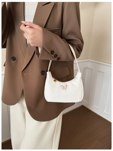 Sac à main blanc en croissant avec décor papillon et pendentif coeur porté par modèle