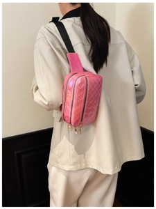Détail d'un sac banane rose vif tissé avec trois fermetures éclair dorées et sangle