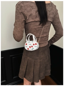 Mini cherry print crossbody bag for kids with gold chain strap shown on model back