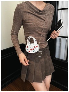 Detail of white mini crossbody bag with cherry prints and golden chain strap