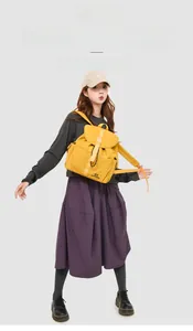 Detail of yellow nylon backpack featuring buckle flap closure and adjustable straps