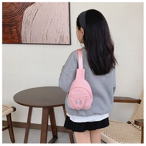Close-up of pink nylon kids crossbody bag featuring a blue drawstring pocket detail