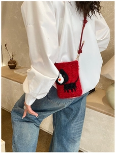 Close-up of handmade red crochet puppy shoulder bag with woven texture and gold metal clasp