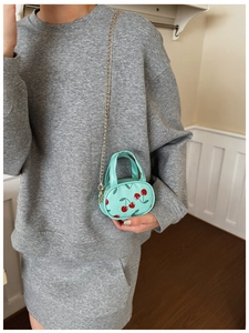 Detail of mint green mini cherry crossbody bag with gold chain and top handle