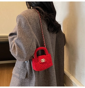 Close-up of red velvet quilted mini bag with gold chain strap worn on grey wool coat