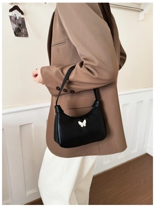 Vue détaillée du sac sous le bras en cuir noir avec un accessoire de papillon blanc 3D