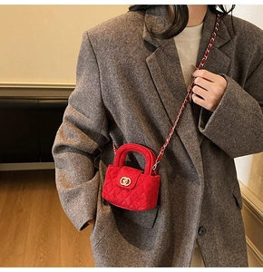 Macro shot of red velvet quilted mini bag with gold logo and chain strap on model