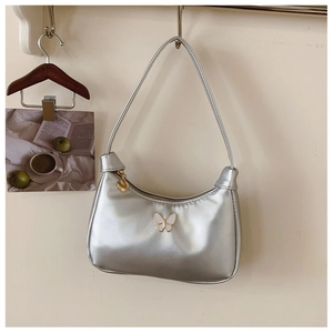 Détail du sac hobo argenté avec boucle papillon et pendentif coeur doré