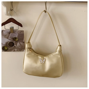 Gros plan du sac en satin champagne doré avec papillon et breloque coeur au zip