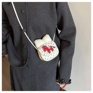 Gros plan du mini sac blanc avec nœud, pois et broderie de poney sur manteau