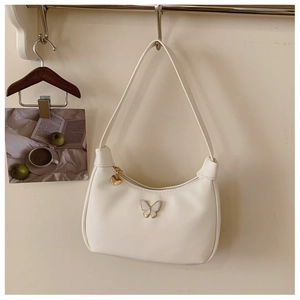 Détail d'un sac hobo beige avec décor papillon et tirette de fermeture en forme de cœur