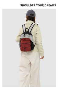 Detail view of a tricolor nylon hiking backpack featuring bungee cords and ergonomic straps