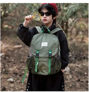 Detail of green checkered kids hiking backpack with MOUNTAINS logo and side mesh pocket