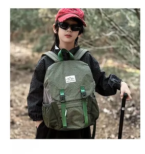 Outdoor detail of kids green plaid hiking backpack with MOUNTAINS patch and buckles