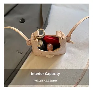 Vue de dessus de l'intérieur du mini sac bandoulière avec rouge à lèvres et poudrier
