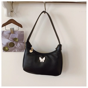 Détail du sac en cuir noir avec patch papillon blanc et pendentif cœur doré
