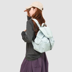 Detail view of mint green nylon backpack with adjustable drawstring and flap closure