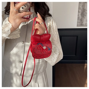 Détail du sac à bandoulière rouge en forme de nœud avec broderie poney et pois