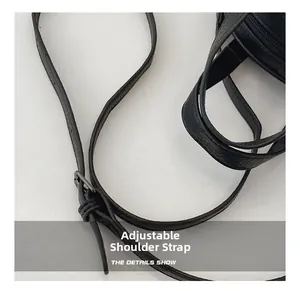 Close-up of adjustable black lychee texture leather shoulder strap with dark metal buckle
