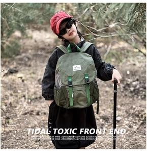 Close-up of green checkered hiking backpack featuring Mountains logo in forest setting