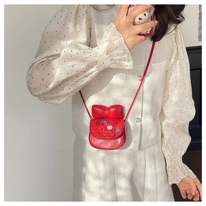 Détail du mini sac bandoulière rouge avec broderie cheval et nœud sur chemise à pois