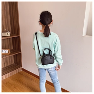 Detailed back view of a child wearing a black litchi pattern mini shell bag
