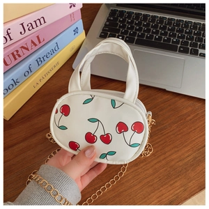 Detailed macro view of white mini cherry crossbody bag with golden chain strap for kids