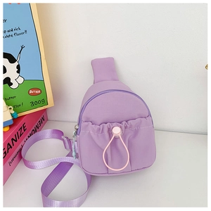 Detail of purple nylon kids crossbody bag with a pink drawstring front pocket on desk