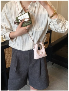 Fille portant un mini sac bandoulière rose à pois avec un joli charm de poupée blanc