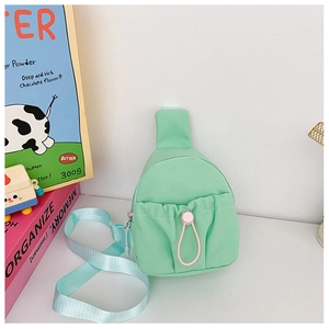 Detail of mint green nylon kids chest bag with light blue strap and pink buckle decoration