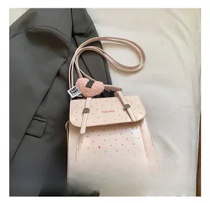 Detail of pink polka dot handbag with a heart plush pendant and branded logo