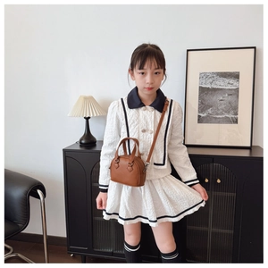 Detail of a brown lychee pattern mini shell handbag paired with a girls' white textured outfit