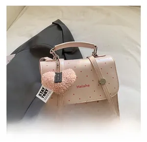 Detail shot of light pink polka dot bag with silver buckle and plush heart charm