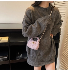 Detail of purple quilted mini crossbody bag with gold chain strap on a grey knit sweater
