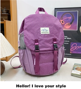 Detail view of purple plaid hiking backpack with MOUNTAINS label and secure buckle straps