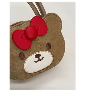 Detailed close-up showing brown suede bear bag texture with fine red leather bow embroidery