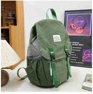 Close-up of green plaid hiking backpack with MOUNTAINS logo and buckle details