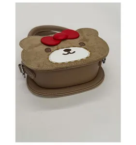 Detail of cute bear-shaped handbag showing plush texture and red bow decoration