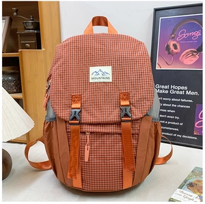 Close-up of orange plaid kids hiking backpack with dual buckles and mountain patch