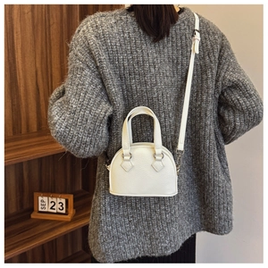 Mini white shell bag with lychee grain texture shown on model in cozy winter outfit