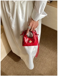 Détail du mini sac rouge avec imprimés cœurs, breloque ours et broderie Bennie
