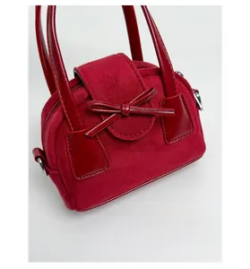 Detalle del mini bolso rojo con texturas de ante y un lazo decorativo elegante