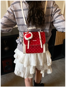 Rear view of a child wearing a red and white polka dot backpack with a cute cherry plush