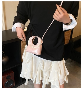 Pink patent leather mini crossbody bag with white lace trim and round handle