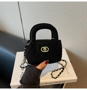 Close-up of black quilted velvet girl's handbag with gold chain and metal clasp