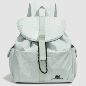 Close-up of mint green nylon backpack with front buckle closure and logo detail