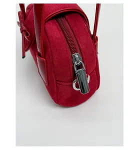 Primer plano de una cremallera de metal plateado en un mini bolso de ante rojo con cuero