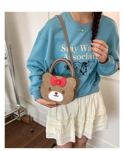 Detail of cute brown bear plush handbag with red bow on blue sweatshirt outfit